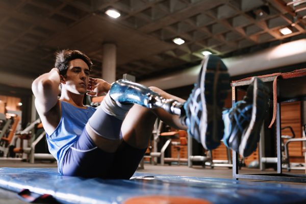 man with prosthetic leg doing crunches in a gym