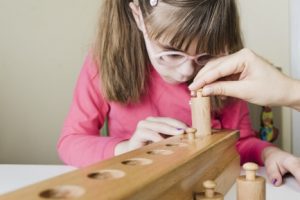 child in a pink shirt playing with a wooden toy