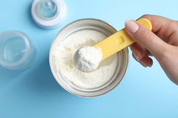 Woman taking powdered infant formula with scoop