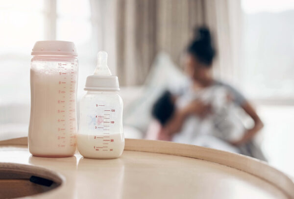 Baby bottle with mother and child in background